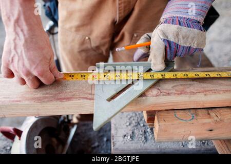 Closeup of male construction worker measuring wood for cut Stock Photo