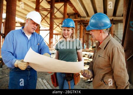 Group of construction workers looking over plans Stock Photo