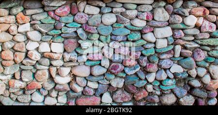 Wall tiled with round colored stones. It is used for decorative purposes. Close up. Stock Photo