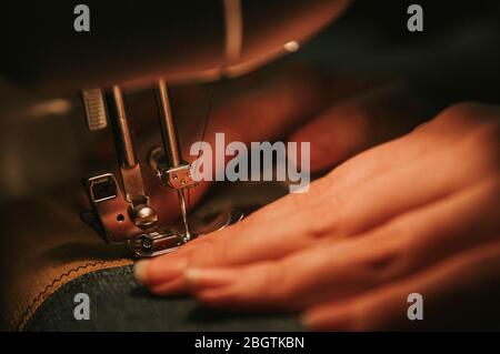 Old sewing machine with black thread scissors and needle, on a old grungy work table. Stock Photo