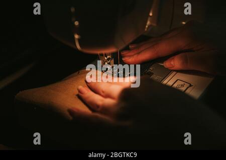 Old sewing machine with black thread scissors and needle, on a old grungy work table. Stock Photo
