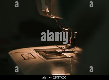 Old sewing machine with black thread scissors and needle, on a old grungy work table. Stock Photo