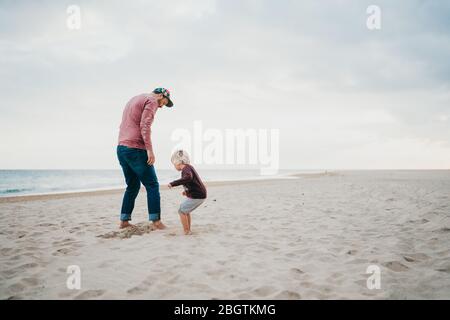 Father and child son playing a the beach on a cloudy day