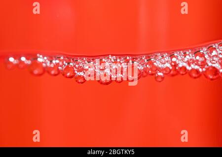Red detergent bubbles in macro view Stock Photo