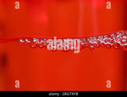 Red detergent bubbles in macro view Stock Photo
