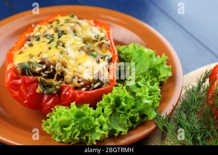 Stuffed red pepper with greens on plate on table close up Stock Photo
