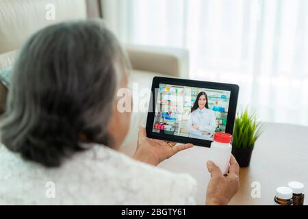 Asian senior woman using video conference, make online consultation with pharmacy consulting about illness and medication via video call. Telehealth, Stock Photo
