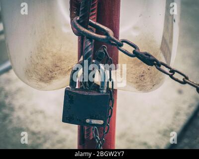 Rusty padlock hangs on a red pipe with a chain Stock Photo