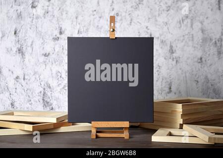Black blank cotton canvas for acrylic and oil paints, a wooden easel and stretcher bars on table Stock Photo