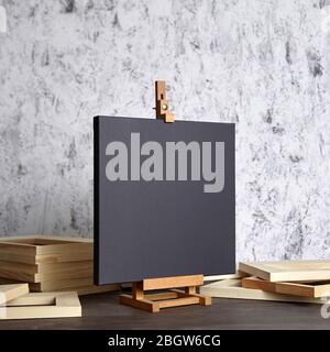 Black blank cotton canvas for acrylic and oil paints, a wooden easel and stretcher bars on table Stock Photo