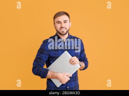 Male programmer with laptop on color background Stock Photo