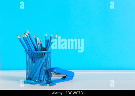Holder with stationery on table against color background Stock Photo