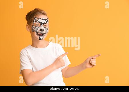 Funny little boy with face painting pointing at something on color background Stock Photo