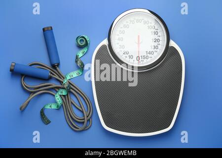 Weight scales with measuring tape, jumping rope and dumbbells on color ...