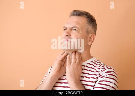 Mature man checking thyroid gland on color background Stock Photo