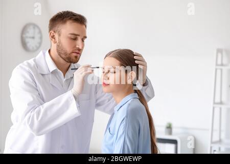 Plastic surgeon applying marks on woman's face in clinic Stock Photo