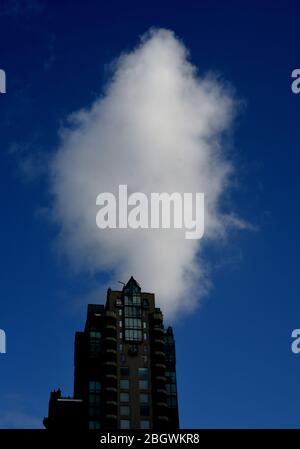 A vertical white cloud sits in a dark blue sky over a modern apartment condo style building in the West End in Vancouver, British Columbia, Canada. Stock Photo