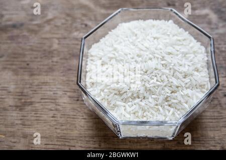 White rice grains in glass bowl top view on wooden background. Stock Photo