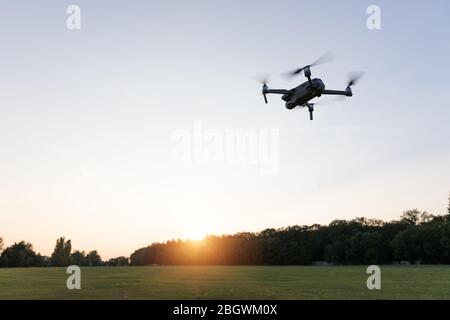 Drone flying over landscape. UAV drone copter flying with digital camera. Drone flying overhead in cloudy blue sky. Quad copter is flying over the  fi Stock Photo