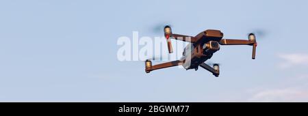 Drone flying over landscape. UAV drone copter flying with digital camera. Drone flying overhead in cloudy blue sky. Quad copter is flying over the  fi Stock Photo