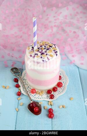 Cranberry milk dessert in glass jar, on color wooden table, on bright background Stock Photo