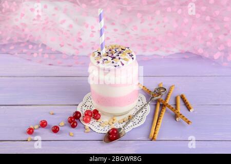 Cranberry milk dessert in glass jar, on color wooden table, on bright background Stock Photo