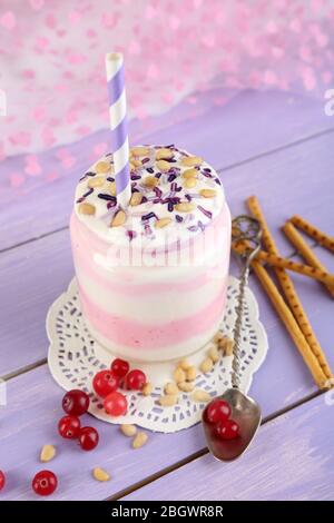 Cranberry milk dessert in glass jar, on color wooden table, on bright background Stock Photo