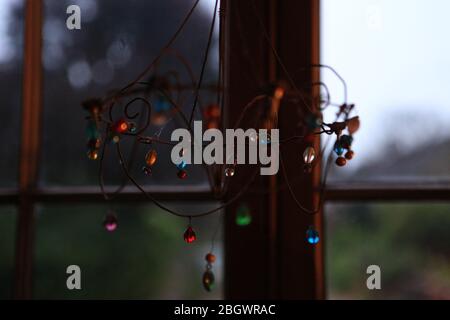 warm shining jewels hanging in a window reflecting the warm lighting in the room Stock Photo