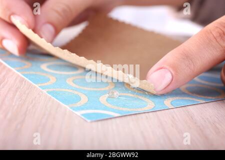 Woman's hand making postcard with a help of glue gun Stock Photo