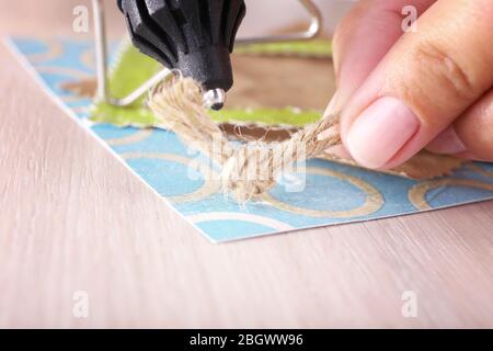 Woman's hand making postcard with a help of glue gun Stock Photo