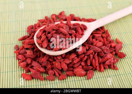 Goji berries in wooden spoon on bamboo mat background Stock Photo