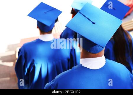 Graduate students wearing graduation hat and gown, outdoors Stock Photo