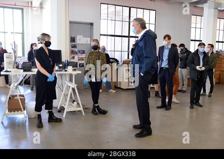 New York City, USA. 22nd Apr, 2020. New York City Mayor Bill de Blasio (3rd from left) talks to the staff of Malia Mills, a fashion garment factory, which now sews non-woven polypropylene hospital gowns for frontline ?healthcare workers, in Industry City in the New York City borough of Brooklyn, NY, April 22, 2020. (Anthony Behar/Sipa USA) Credit: Sipa USA/Alamy Live News Stock Photo