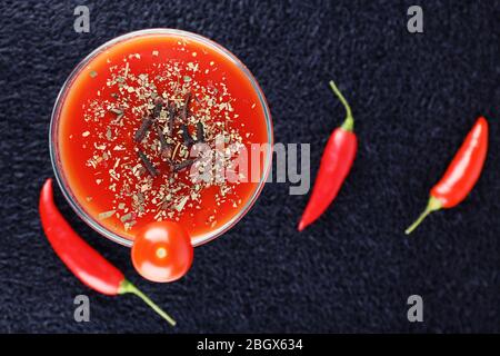 Tomato juice in goblet, chilly pepper and fresh tomatoes on dark background Stock Photo