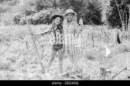 Growing vegetables. Hope for nice harvest. Girls planting plants. Rustic children working in garden. Planting and watering. Agriculture concept. Sisters together helping at farm. Planting vegetables. Stock Photo