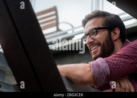 A bearded hipster man wearing a red button down shirt smiling with his prescribed glasses to see more clearly what is in the distance with a straight Stock Photo
