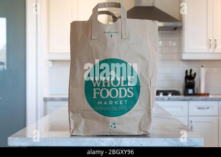 Whole Foods Market grocery bag placed on the counter in a kitchen. Stock Photo