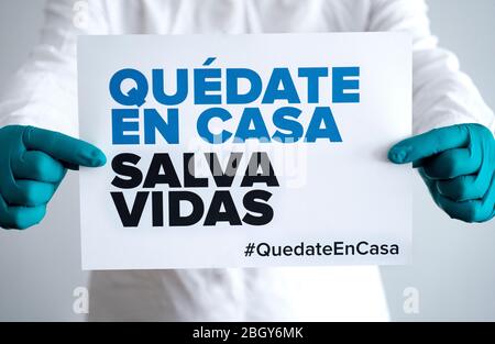 Doctor holding sign 'Stay Home Save Lifes' in Spanish, global message for the coronavirus crisis. Quarantine message across the globe to fight COVID-1 Stock Photo