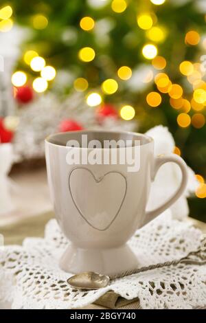 Mug with hot drink and Christmas decorations on fir tree background Stock Photo