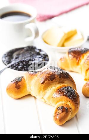 Sweet homemade croissants with poppy, jam and butter on white table. Stock Photo