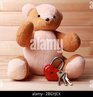 Teddy Bear with padlock in shape of heart on wooden background Stock Photo