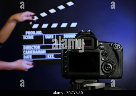 Hands with movie clapper board in front of camera on dark background Stock Photo