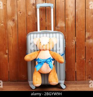 Suitcase with teddy bear on wooden planks background Stock Photo