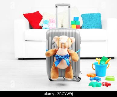 Suitcase with teddy bear and child toys in room on white sofa background Stock Photo