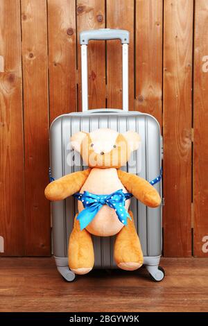 Suitcase with teddy bear on wooden planks background Stock Photo