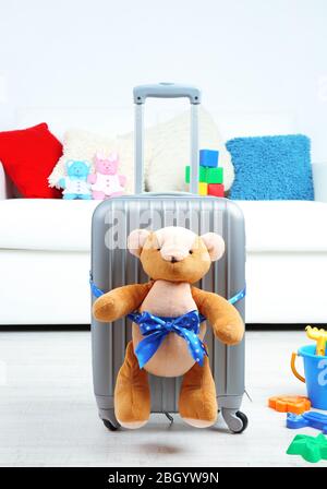 Suitcase with teddy bear and child toys in room on white sofa background Stock Photo