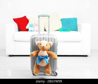 Suitcase with teddy bear in room on white sofa background Stock Photo