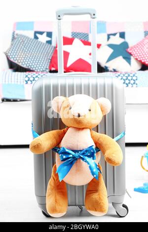 Suitcase with teddy bear and child toys in room on white sofa background Stock Photo