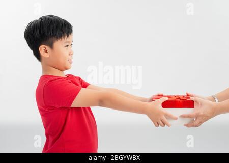 Take this present! Side view of cheerful generous good-natured little boy offering gift box and smiling happily Stock Photo