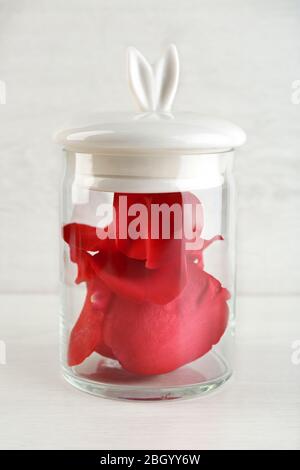 Rose petals in glass jar on light background Stock Photo